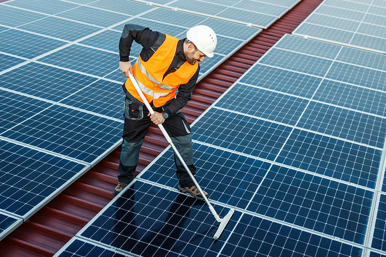 Ouvrier en train de nettoyer des panneaux solaires pour assurer leur maintenance
